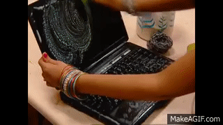 Uma mulher, vestida com roupas tradicionais indianas, limpa um laptop com esponja e sabão.