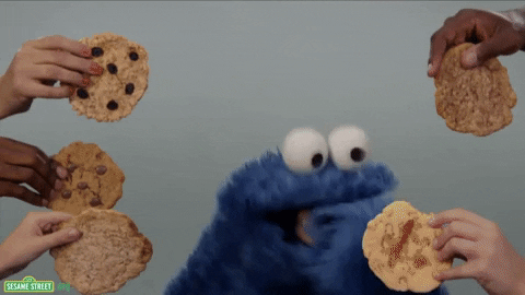 Personagem Come Come (Cookie Monster), de Vila Sésamo, comendo cookies que são oferecidos por mãos humanas.