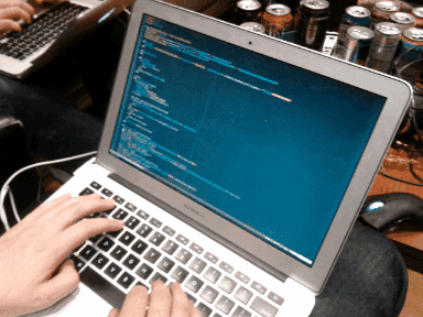 Mãos digitando em um notebook. Na tela, código é escrito no terminal.