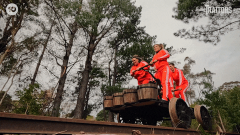 4 pessoas vestindo vermelho, operando um vagão sobre trilhos.